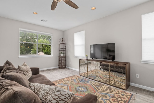 living area featuring wood finished floors, a healthy amount of sunlight, a ceiling fan, and visible vents