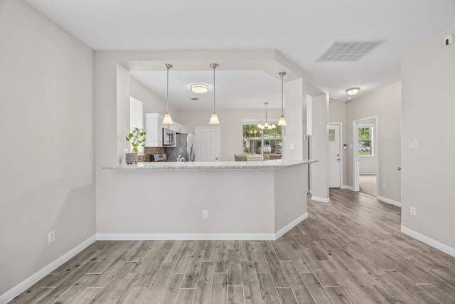 kitchen with appliances with stainless steel finishes, visible vents, a healthy amount of sunlight, and light wood finished floors