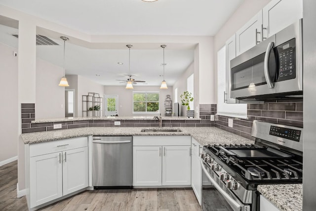 kitchen featuring light stone countertops, stainless steel appliances, light wood-style flooring, and a sink