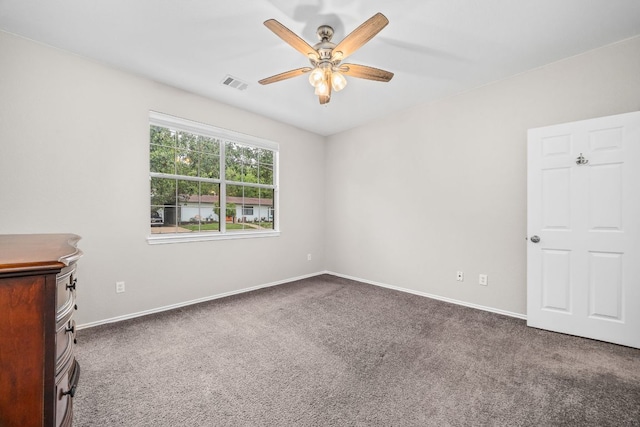 spare room with carpet, visible vents, a ceiling fan, and baseboards