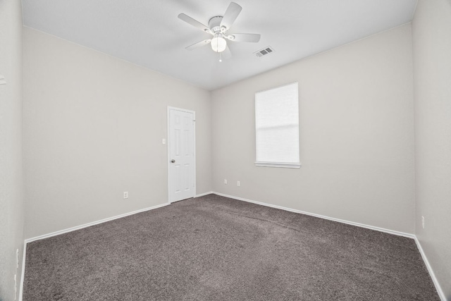 unfurnished room with visible vents, dark carpet, ceiling fan, and baseboards