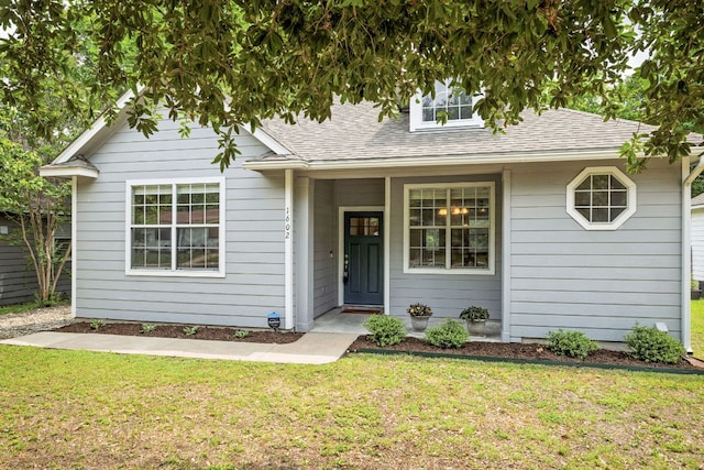 view of front facade with roof with shingles and a front lawn
