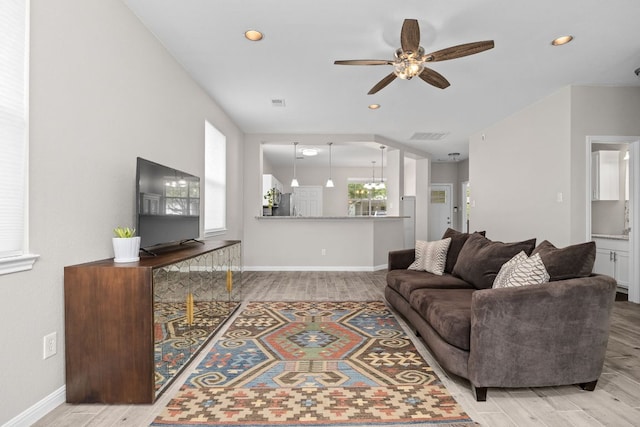 living room with wood finished floors, plenty of natural light, a ceiling fan, and baseboards