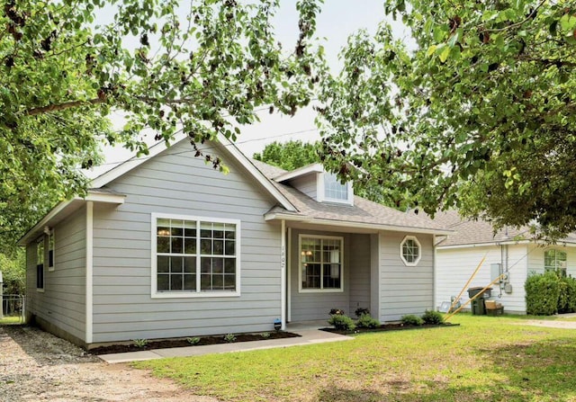 view of front of property featuring a shingled roof and a front lawn