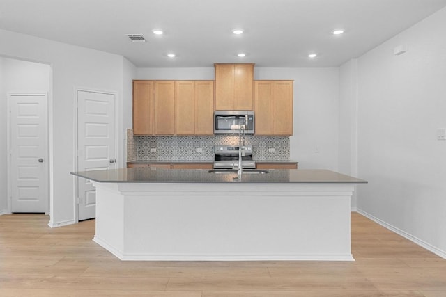 109 Coastal Way, Georgetown, TX 78628 - kitchen featuring appliances with stainless steel finishes, a sink, a center island with sink, light wood finished floors, and recessed lighting