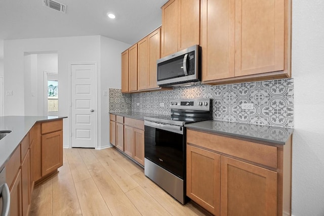 109 Coastal Way, Georgetown, TX 78628 - kitchen with appliances with stainless steel finishes, light wood-style flooring, backsplash, dark countertops, and recessed lighting