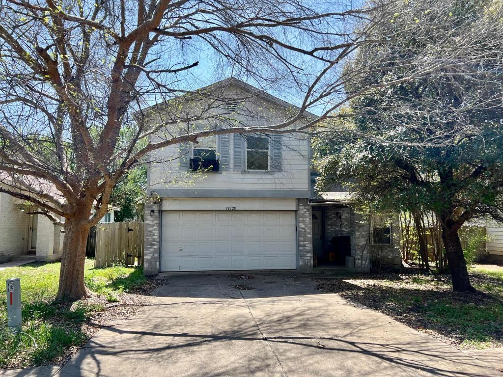 traditional-style house with driveway, an attached garage, and fence
