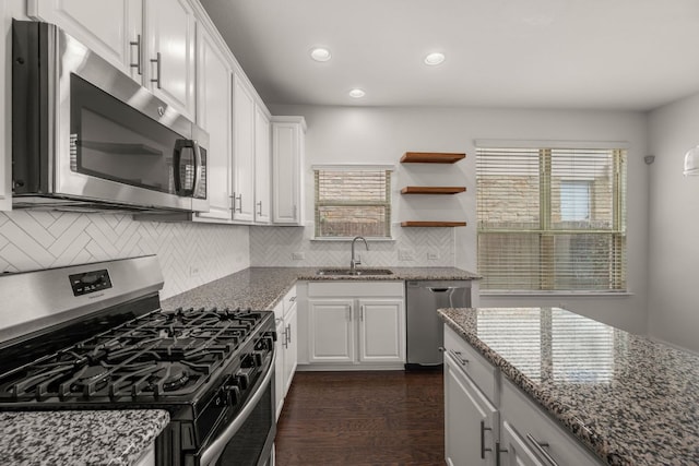 kitchen featuring tasteful backsplash, a sink, white cabinets, stone countertops, and stainless steel appliances
