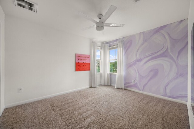 carpeted spare room featuring visible vents, a ceiling fan, and baseboards