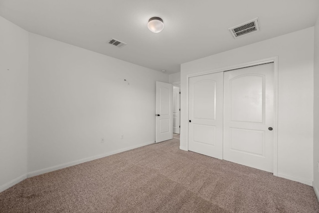 unfurnished bedroom with visible vents, carpet, baseboards, and a closet