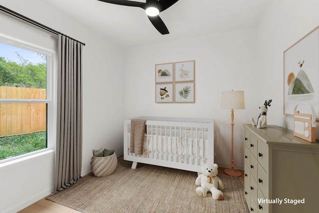 bedroom with ceiling fan and a nursery area