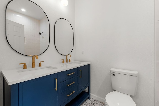 bathroom with baseboards, toilet, double vanity, and a sink