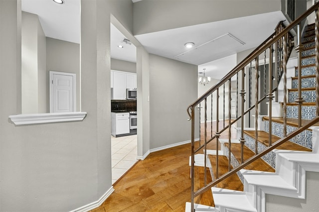 staircase featuring visible vents, baseboards, recessed lighting, wood finished floors, and a notable chandelier
