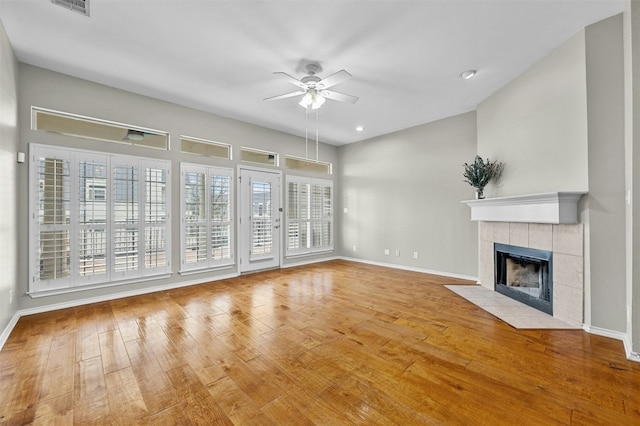 unfurnished living room with baseboards, hardwood / wood-style flooring, ceiling fan, and a tile fireplace