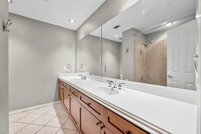 bathroom featuring a tile shower, a sink, visible vents, baseboards, and tile patterned flooring