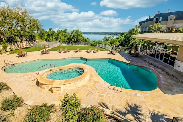 pool with fence, a community hot tub, a water view, and a patio area