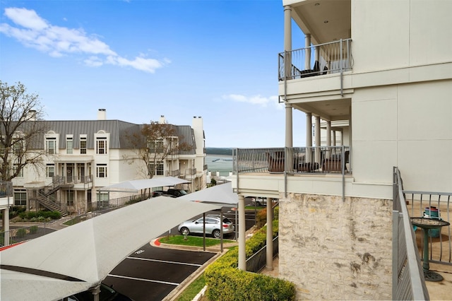 exterior space featuring a balcony and covered and uncovered parking