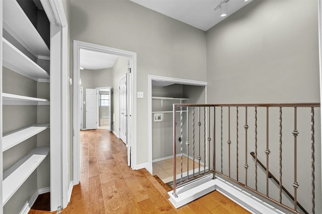 corridor featuring wood finished floors and an upstairs landing