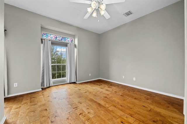 spare room featuring a ceiling fan, visible vents, hardwood / wood-style flooring, and baseboards