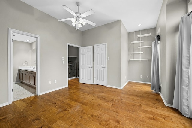 unfurnished bedroom with ceiling fan, ensuite bathroom, light wood finished floors, and baseboards
