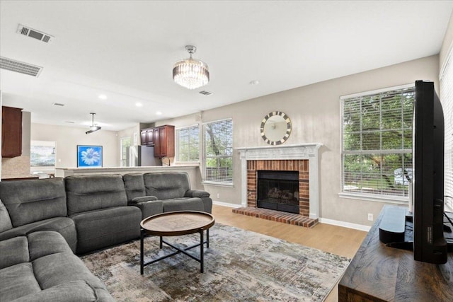 living area with a wealth of natural light, visible vents, light wood finished floors, and baseboards