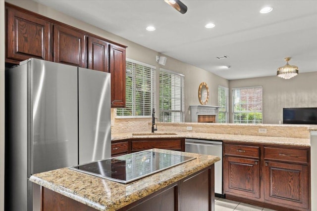 kitchen with a sink, visible vents, stainless steel appliances, open floor plan, and light stone countertops