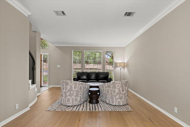 living room with ornamental molding, visible vents, wood finished floors, and baseboards