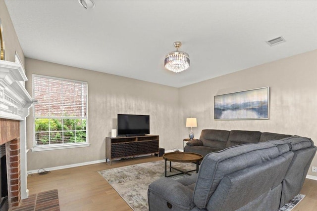 living room with baseboards, visible vents, wood finished floors, and a fireplace