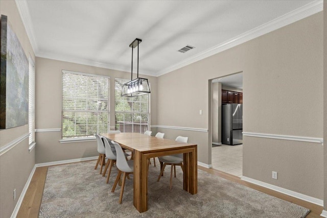 dining space with baseboards, visible vents, and crown molding