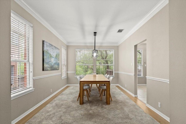 dining room featuring ornamental molding, visible vents, wood finished floors, and baseboards