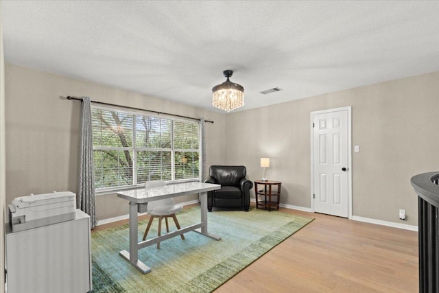 interior space with a notable chandelier, visible vents, wood finished floors, and baseboards