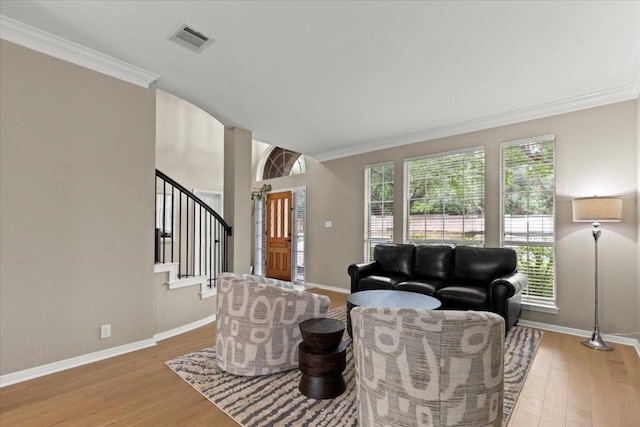 living room featuring wood finished floors, stairs, baseboards, visible vents, and crown molding