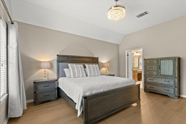 bedroom featuring visible vents, a notable chandelier, light wood finished floors, and vaulted ceiling