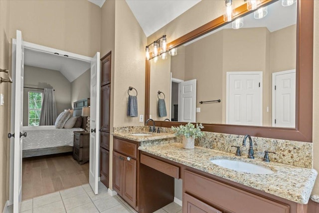 bathroom featuring tile patterned flooring, a sink, lofted ceiling, and ensuite bath
