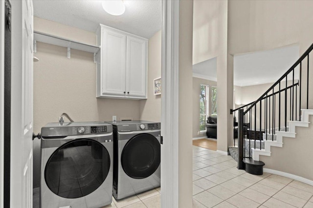 laundry area with cabinet space, washer and clothes dryer, light tile patterned floors, crown molding, and baseboards
