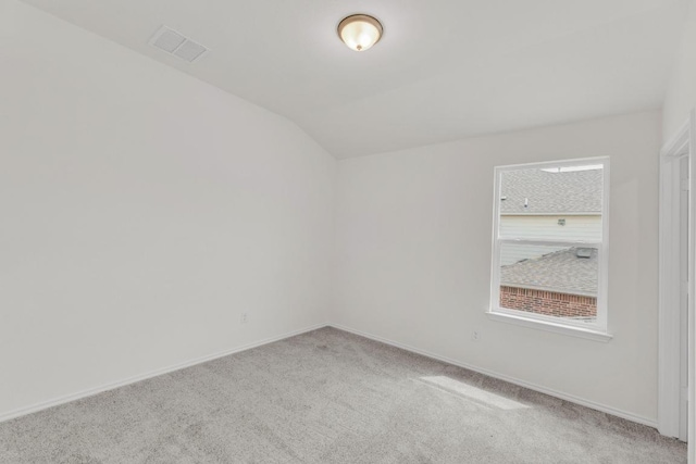 empty room with baseboards, visible vents, vaulted ceiling, and carpet