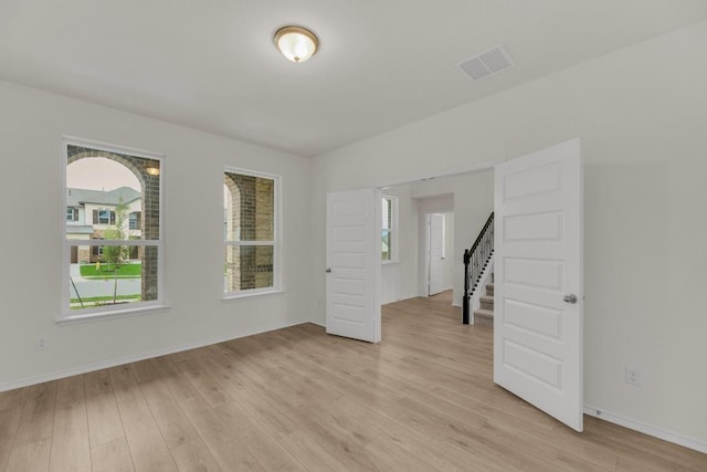 spare room with stairs, baseboards, visible vents, and light wood-style flooring