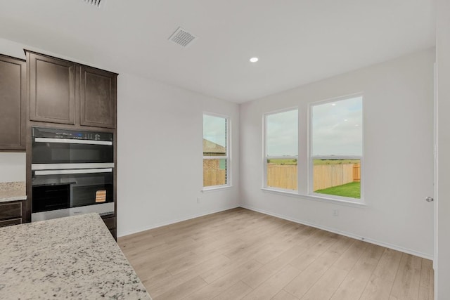 kitchen with visible vents, light wood-style floors, dark brown cabinetry, and double oven