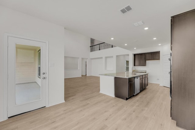 kitchen with dark brown cabinetry, a sink, dishwasher, light wood-type flooring, and visible vents