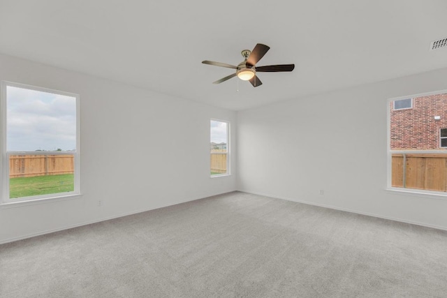 carpeted spare room with visible vents, baseboards, and ceiling fan