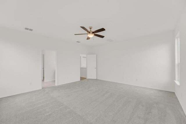 spare room featuring carpet floors, ceiling fan, and visible vents
