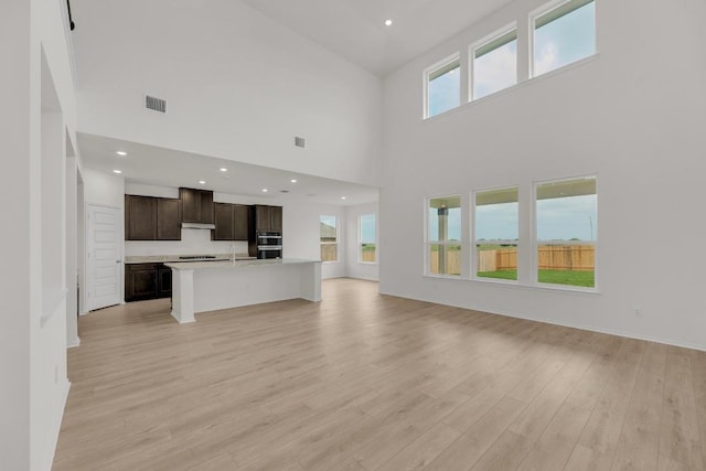 4847 Padula Dr, Round Rock, TX 78665 - unfurnished living room featuring light wood-style flooring, a high ceiling, and recessed lighting