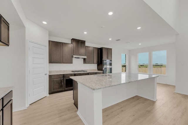kitchen with dark brown cabinetry, gas cooktop, a sink, and light wood-style flooring