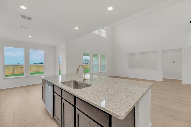 kitchen with visible vents, open floor plan, light wood-type flooring, a sink, and dishwasher