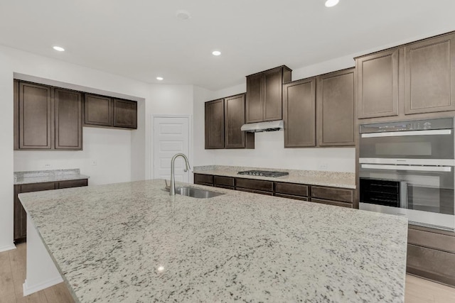 kitchen featuring a sink, dark brown cabinetry, stainless steel appliances, and an island with sink