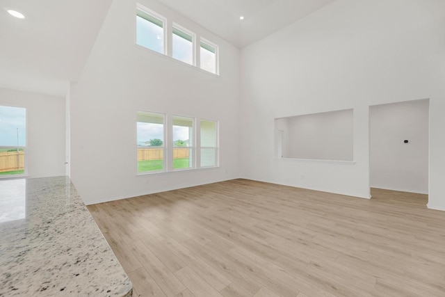 unfurnished living room featuring light wood-style floors and high vaulted ceiling
