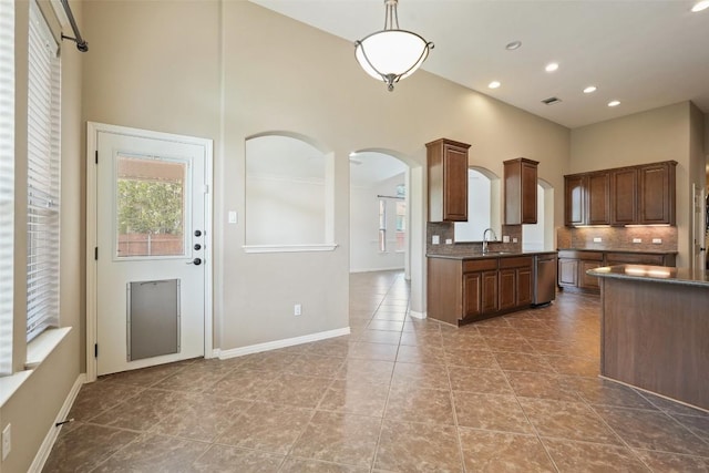 2213 Settlers Park Loop, Round Rock, TX 78665 - kitchen with stainless steel dishwasher, a high ceiling, dark countertops, arched walkways, and tasteful backsplash