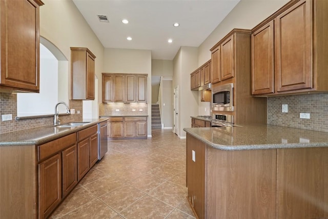2213 Settlers Park Loop, Round Rock, TX 78665 - kitchen with stainless steel appliances, a peninsula, tasteful backsplash, a sink, and brown cabinets