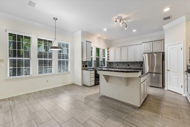 kitchen with tasteful backsplash, visible vents, a kitchen island, dark countertops, and freestanding refrigerator
