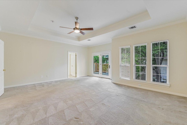carpeted spare room featuring ornamental molding, visible vents, ceiling fan, and a tray ceiling